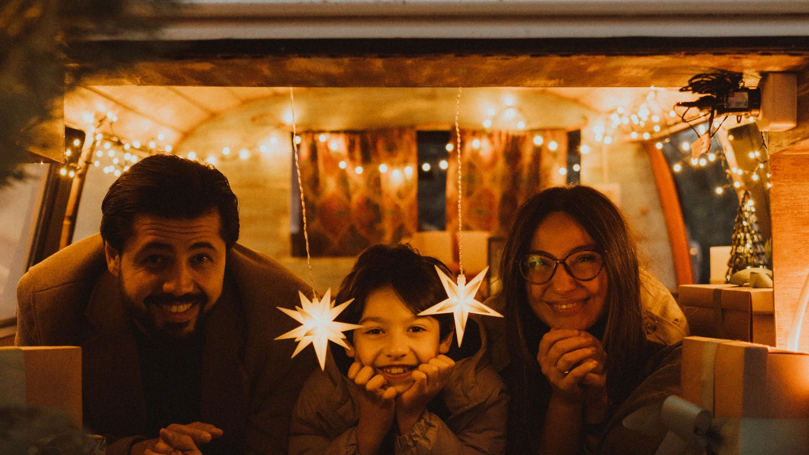 Family smiling together inside a warmly lit van during the holidays