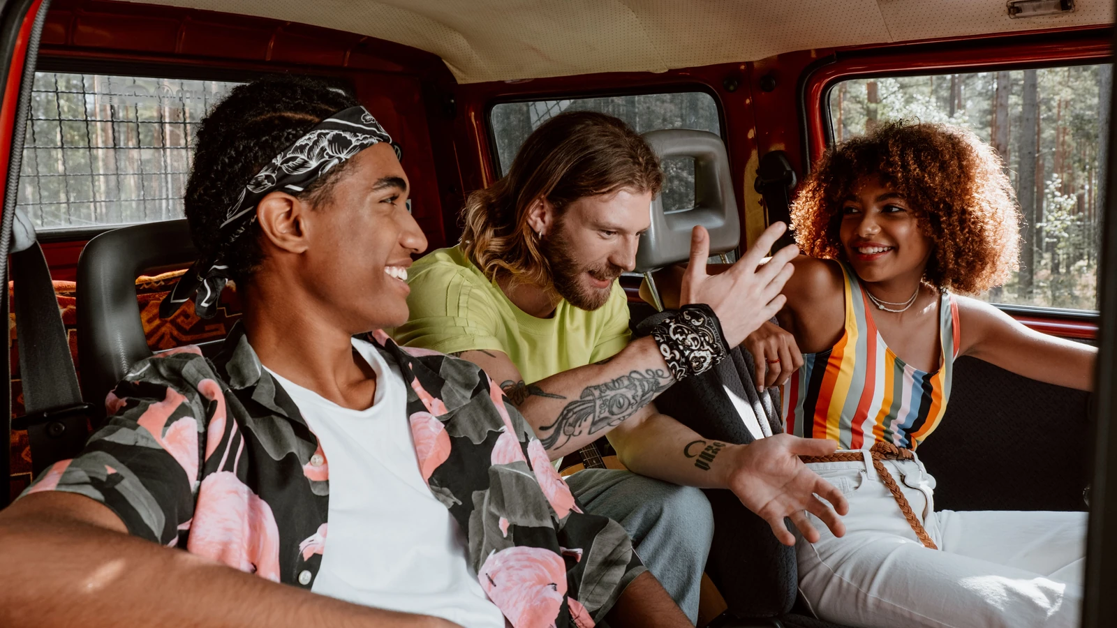Three friends sharing an easy conversation inside a red van