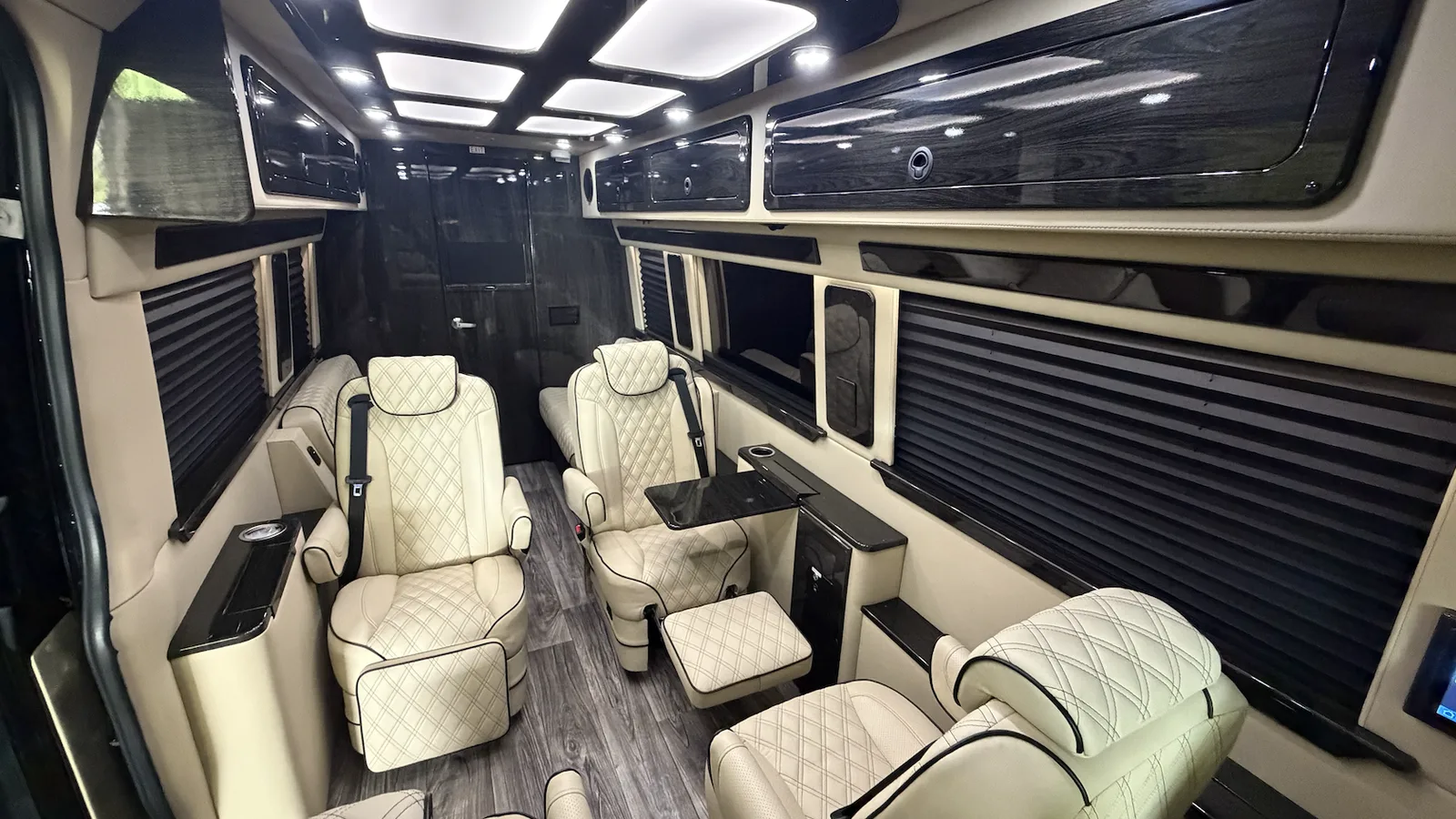Illustrative photo: quilted cream captain's chairs and lit ceiling inside a Dufourfun luxury Sprinter, not photographed at Barrett-Jackson
