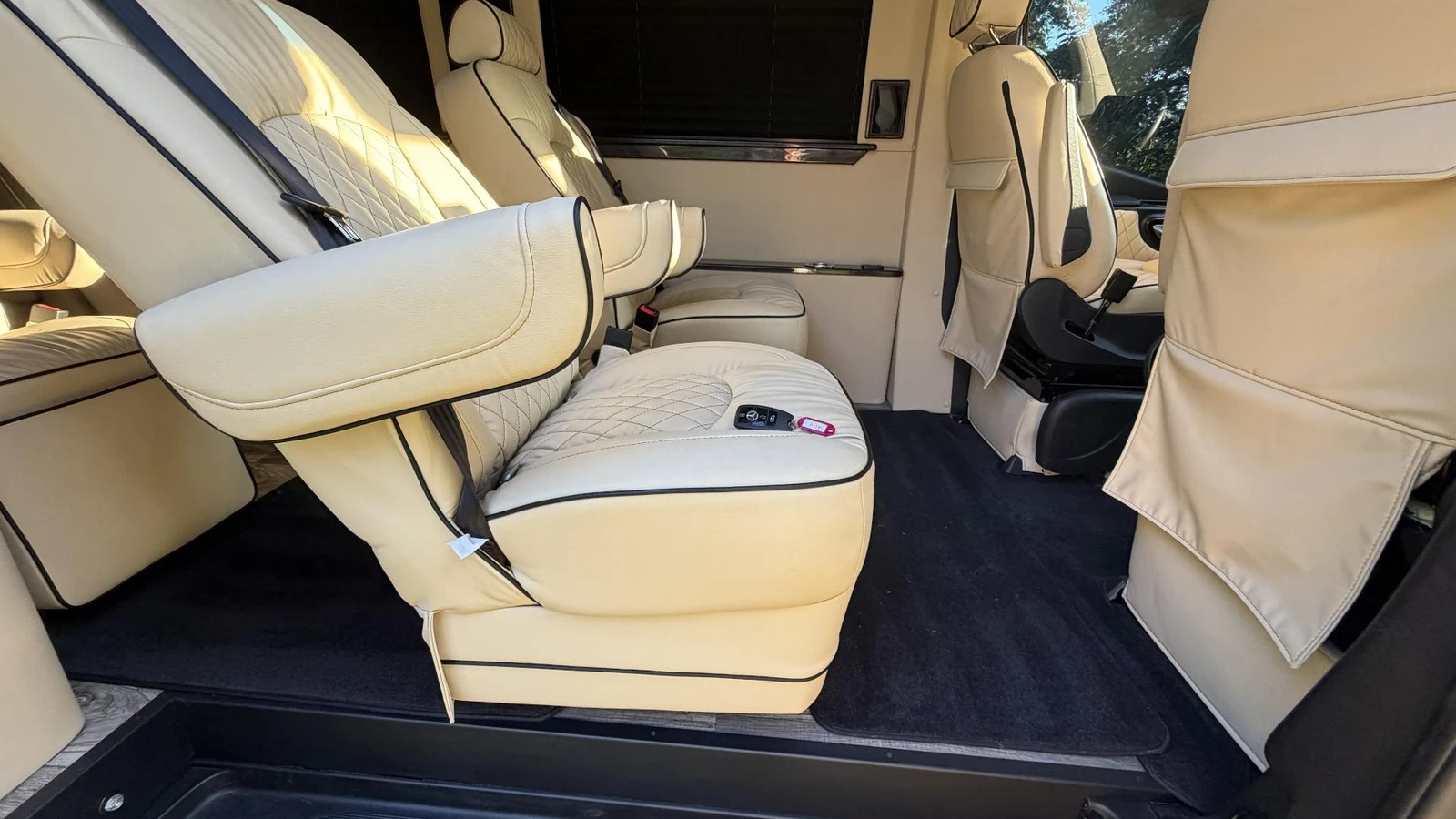 Cream leather luxury van seats and visible seatbelts at the sliding-door entrance for a delivery-day acceptance check