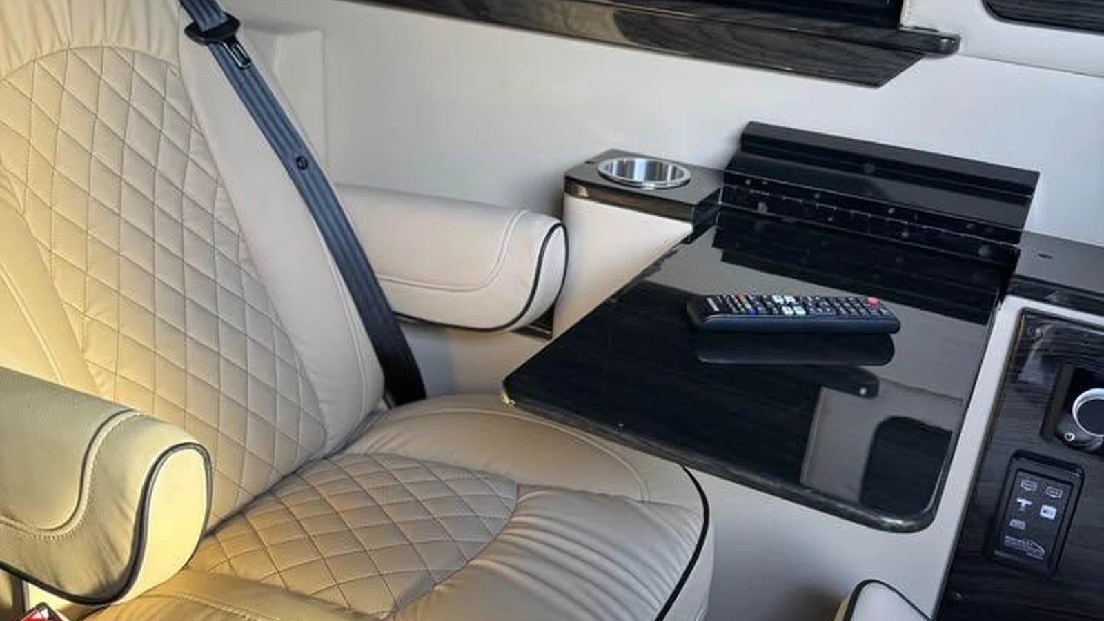Cream leather passenger seat beside a deployed black lap table in a Dufourfun inventory van