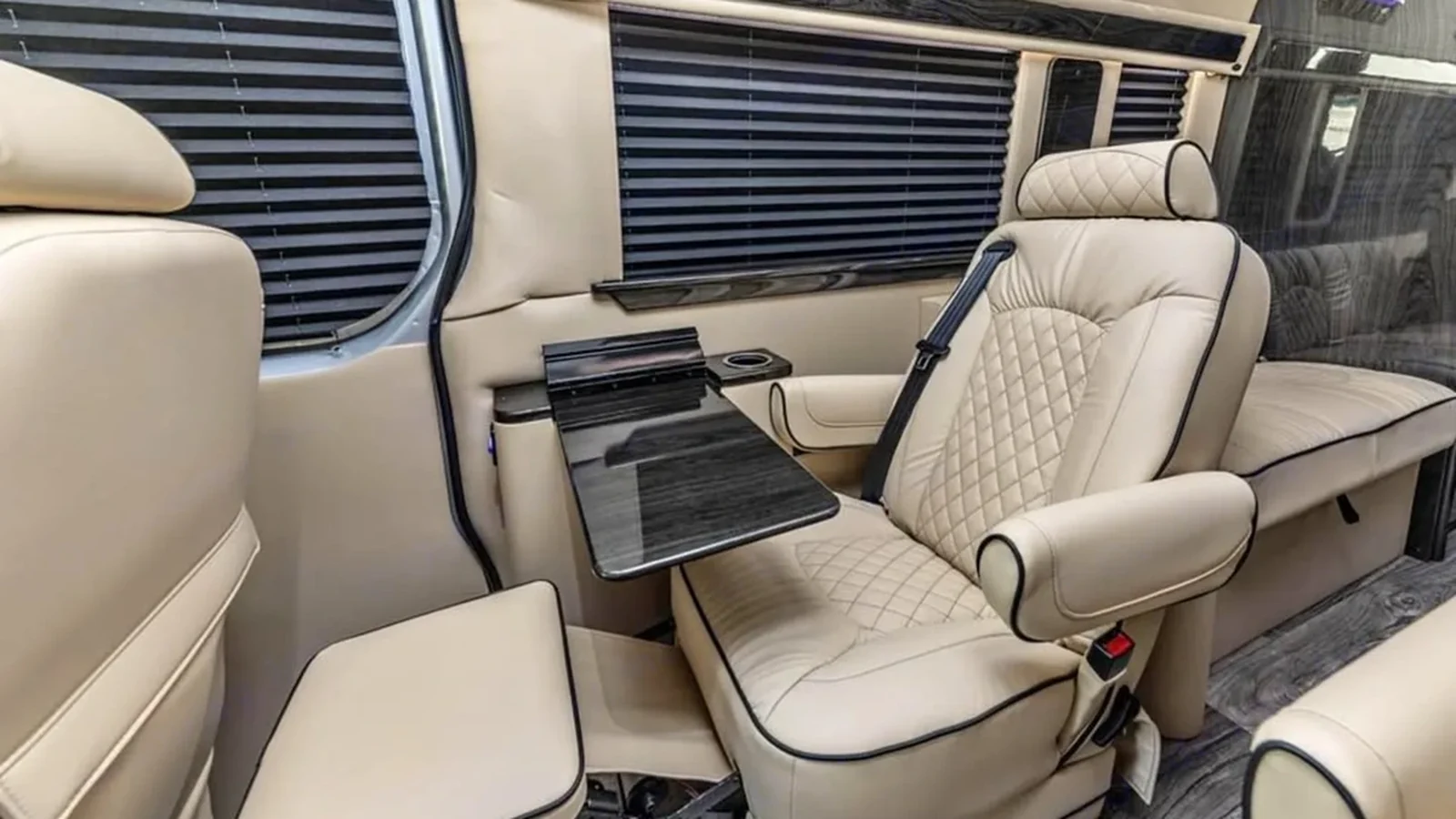 Illustrative luxury-van passenger seating and table for business travel; not an airport or CES event photograph.
